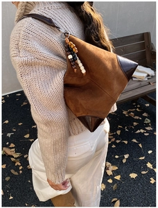Detail view of vintage brown suede crossbody bag with wood bead accents and leather corners