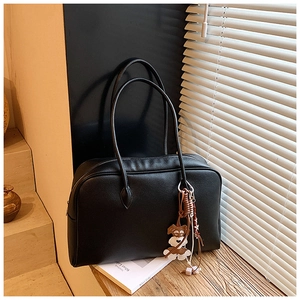 Black litchi grain tote bag with zipper closure and cute dog pendant in warm sunlight