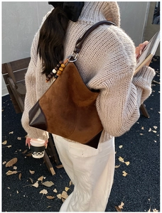 Brown faux suede shoulder bag with wood bead detail shown in a vintage autumn outdoor setting