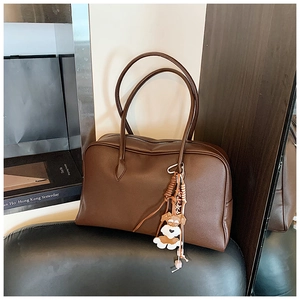 Detail of dark brown lychee leather tote bag with a cute schnauzer cartoon charm