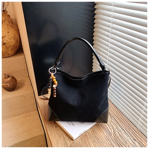 Detailed shot of black faux suede crossbody bag with vintage wooden bead tassel ornament