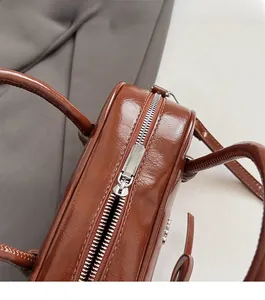 Close-up of vintage brown oil wax leather pillow bag with smooth silver zipper and handles