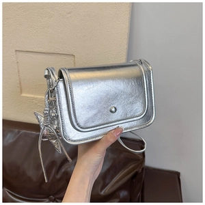 Dettaglio di una borsa quadrata argento con finitura metallica e ciondolo a stella