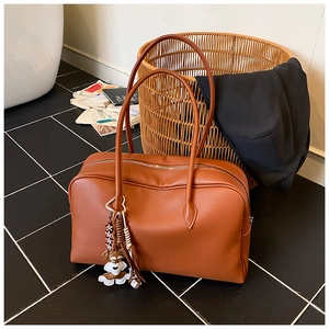 Detailed top view of a brown pebbled leather tote bag with a cute dog charm