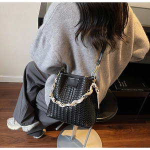 Detail of black woven bucket bag with silk scarf handle and leather texture