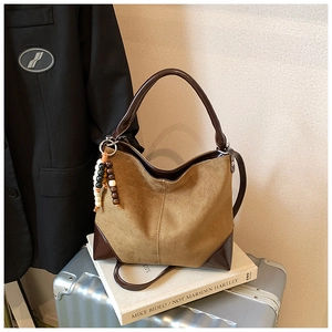 Detail of vintage brown suede tote bag with wooden bead charm and reinforced leather corners