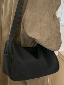 Minimalist black faux suede shoulder bag for women worn with a stylish winter coat