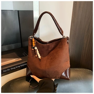 Detail of vintage brown suede tote bag featuring ethnic wooden bead charm and leather handle