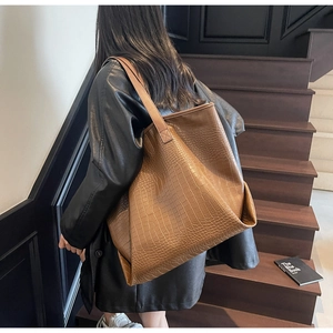 Close-up of brown crocodile embossed leather texture on a large stylish tote bag