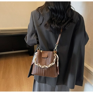Back view of brown woven leather bucket bag with silk scarf and chain on a model