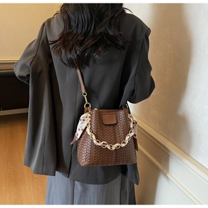 Detail of dark brown woven leather bucket bag with silk scarf on chain strap