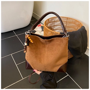 Detail of vintage brown frosted suede tote bag with wooden bead charm and sturdy leather handle
