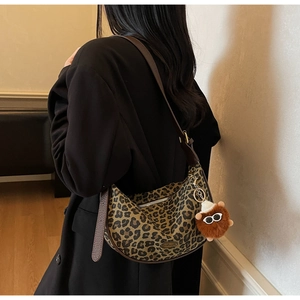 Detailed shot of leopard print hobo bag with wide leather strap and plush charm