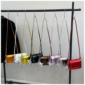 Dettaglio di otto mini borse a tracolla lucide con ciondoli a stella in vari colori metallici