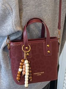 Vintage burgundy leopard print bucket bag with wooden bead charm and long shoulder strap