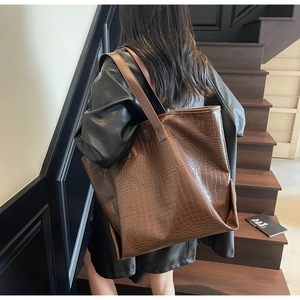 Brown crocodile embossed tote bag shown on model with stylish long shoulder straps