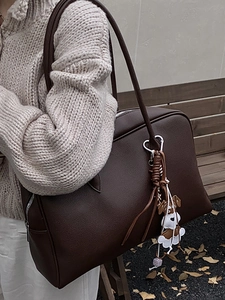 Retro brown leather tote bag with dog charm on a park bench in autumn setting