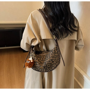 Detail of leopard print canvas bag with dark brown leather straps and plush charm