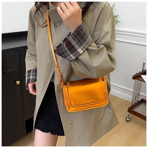 Borsa a tracolla quadrata color arancio dorato metallizzato abbinata a un cappotto kaki