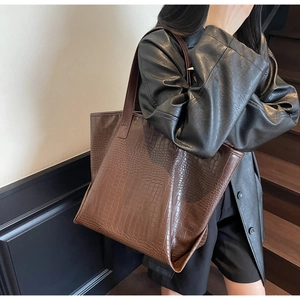 Detail shot of a dark brown tote bag with premium crocodile embossed leather texture