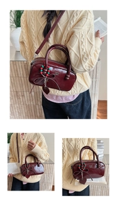 Detail view of burgundy patent leather pillow bag with charms and detachable strap