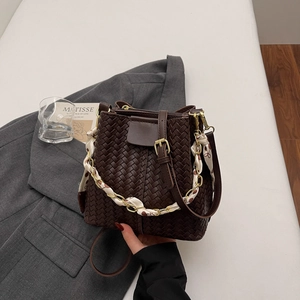Detail of dark brown woven bucket bag featuring a silk scarf wrapped chain handle