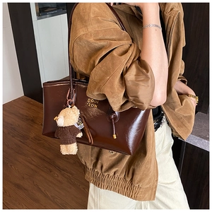 Detail of dark brown faux leather tote bag with gold hardware and bear charm