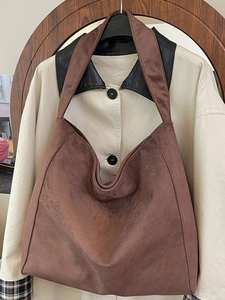 Borsa hobo marrone in pelle scamosciata con ampia tracolla appesa su sfondo neutro