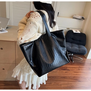 Detail of a large black crocodile pattern tote bag shown in an office setting
