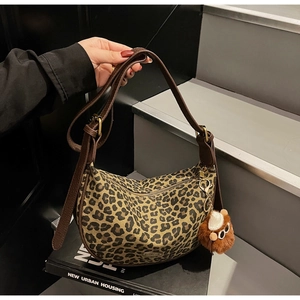 Detail of leopard print dumpling bag with adjustable shoulder strap and plush ball charm