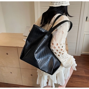 Close-up of black crocodile pattern leather tote bag showing glossy texture and wide strap