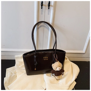 Detail of dark brown glossy tote bag with gold lettering and cute teddy bear charm