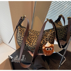 Detail of leopard print crescent bag with brown lychee leather strap and plush eye charm