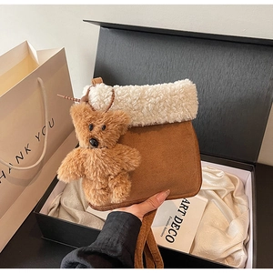 Brown suede crossbody bag with plush white trim and bear charm in a black gift box