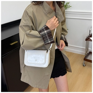 Borsa a tracolla bianca in pelle con perla, indossata su un trench alla moda