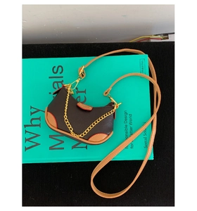 Détail d'un mini sac hobo en cuir litchi marron avec chaîne dorée et bordure passepoilée