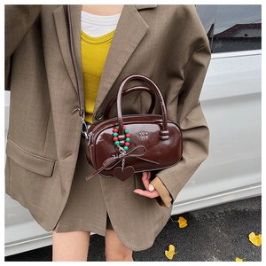 Brown patent leather pillow bag with charms shown in a lifestyle autumn setting