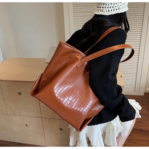 Detail of brown crocodile pattern tote bag with dual straps worn over the shoulder