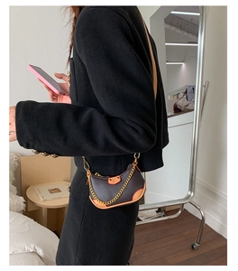 Détail d'un sac bandoulière demi-lune en cuir marron foncé avec chaîne dorée élégante
