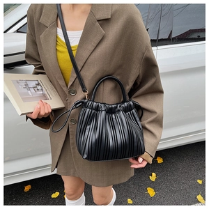 Close-up of black pleated PU leather bucket bag with round handle and detachable strap