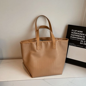Close-up of crocodile embossed texture on large beige tote bag with neat stitching details