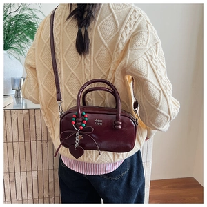 Detail of burgundy patent leather pillow bag with beaded heart charm and COIH 2DN logo