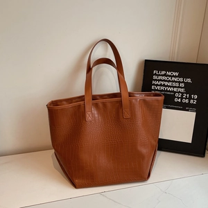 Close-up of deep brown tote bag featuring detailed crocodile embossed texture and PU leather