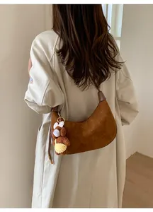 Brown faux suede crescent bag with a cute plush bear pendant shown on model shoulder
