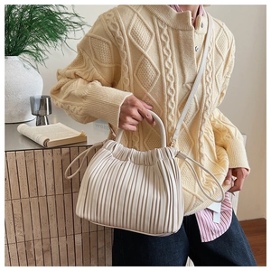 Detail of cream pleated leather bucket bag with vertical folds and drawstrings