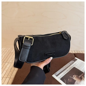 Dettaglio borsa Boston in camoscio nero con fibbia dorata e tracolla in pelle stile retrò