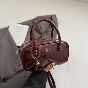 Detail of burgundy glossy patent leather pillow bag with metal star and bead charms