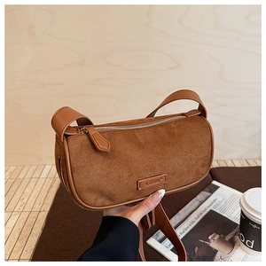 Dettaglio di una borsa Boston in camoscio marrone con etichetta logo e manico largo