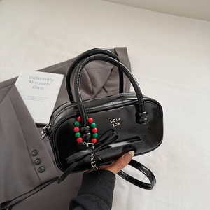 Detail of black glossy patent leather bag with a beaded handle and star bow pendant