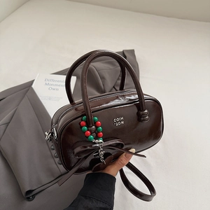 Detail view of glossy chocolate brown pillow bag with chic bow and beaded charm